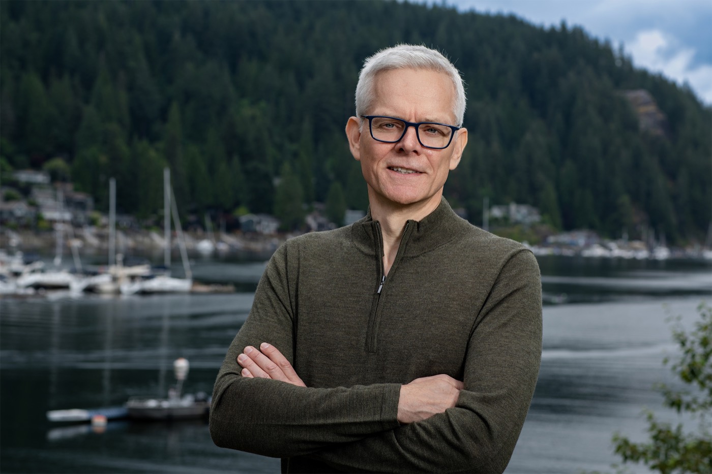 Martin Bush at a waterfront with boats and forested hills